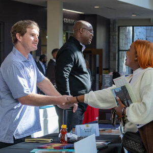 A student and employer shake hands at a career fair.