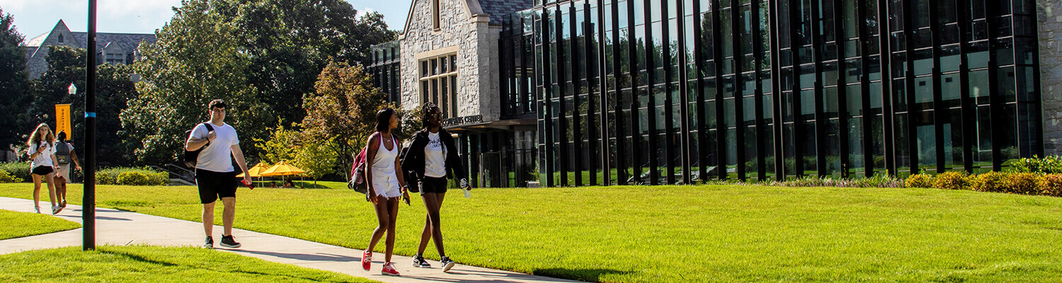 Students walk in front of Cousins Center on a sunny day.