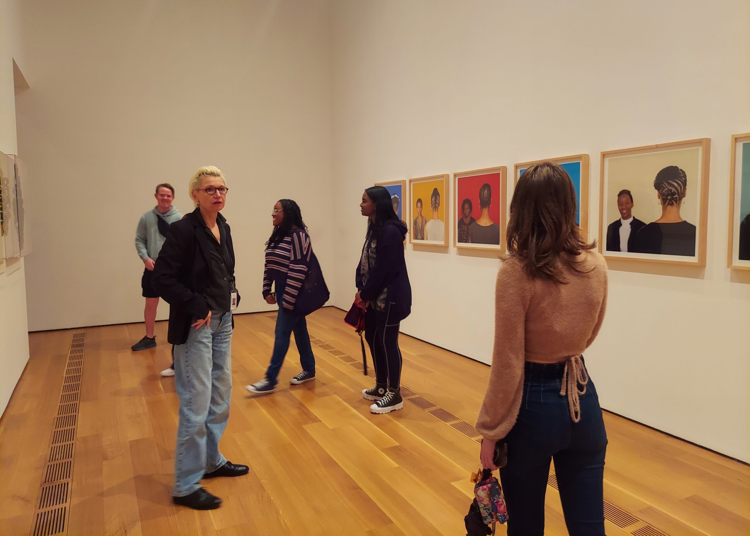 Students walking through Sonya Clark: We Are Each Other exhibition with Dr. Claudia Einecke