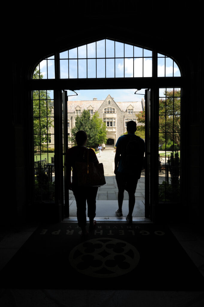 Two students stand in the doorway of Lupton Hall looking toward Hearst Hall