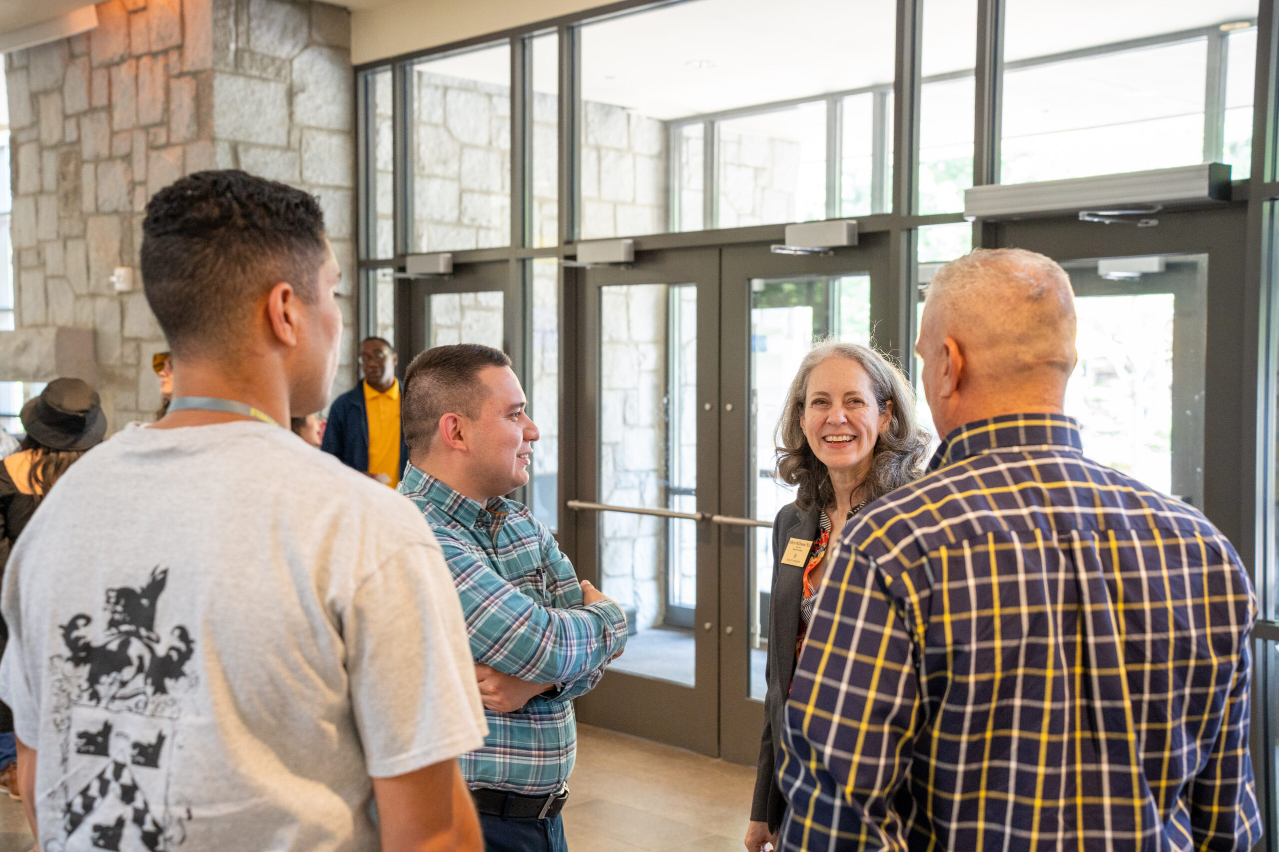 Dr. McClymond smiling while speaking to parents and a student at an orientation event for incoming freshmen.