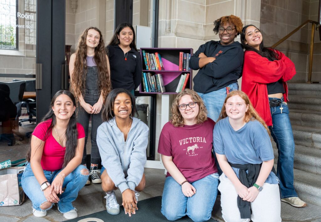 First-year students pose in front of their little library they constructed