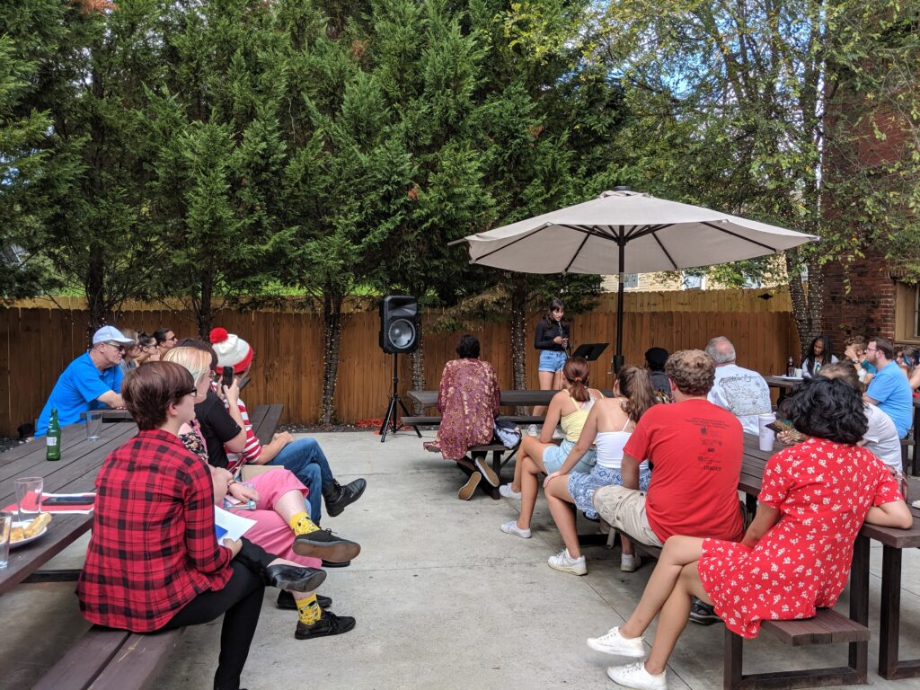 OU Student presents to a crowd seated on picnic tables