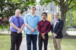 Four men stand on the Oglethorpe campus.