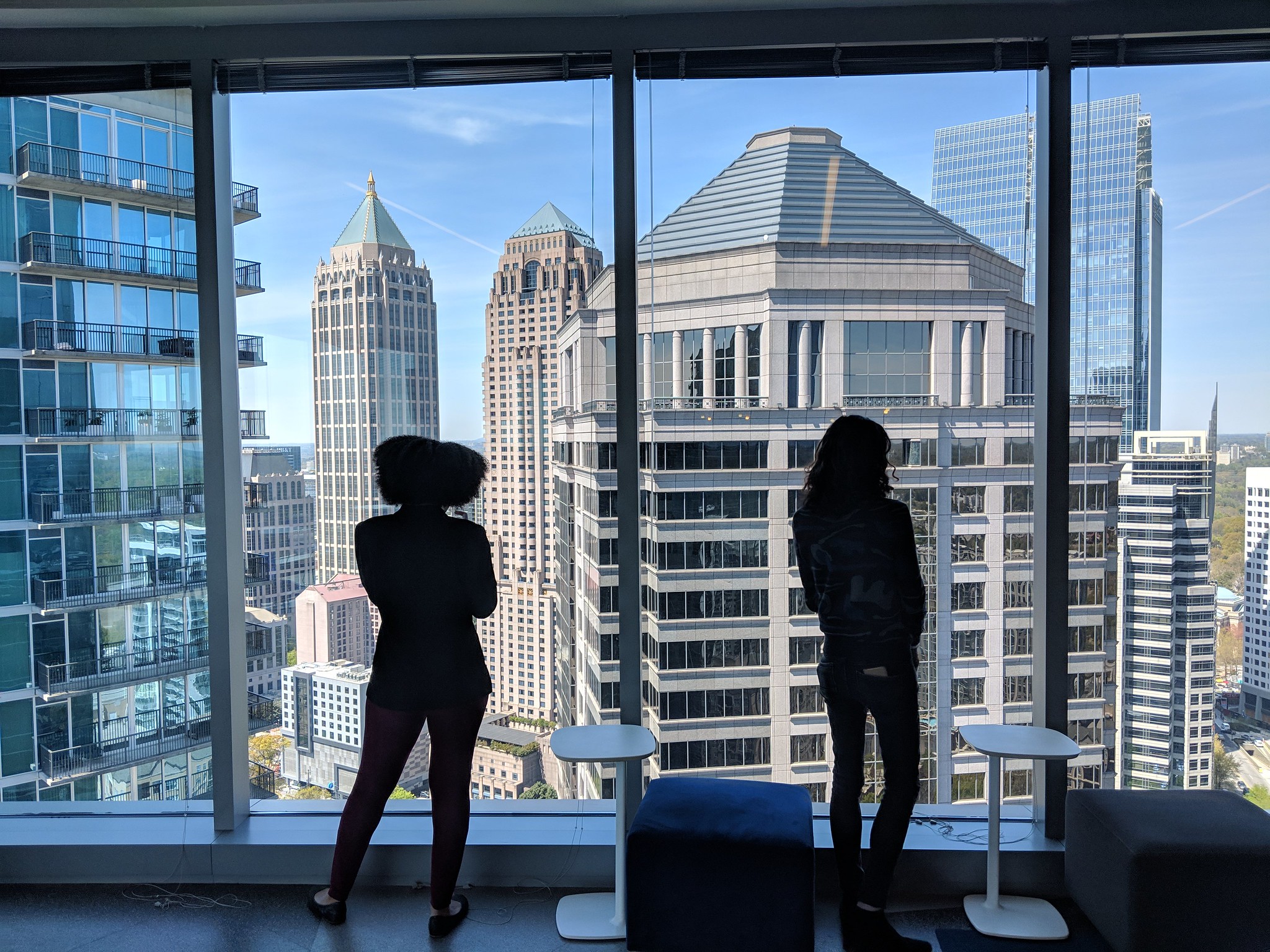 Two students stand in a high rise overlooking Atlanta buildings