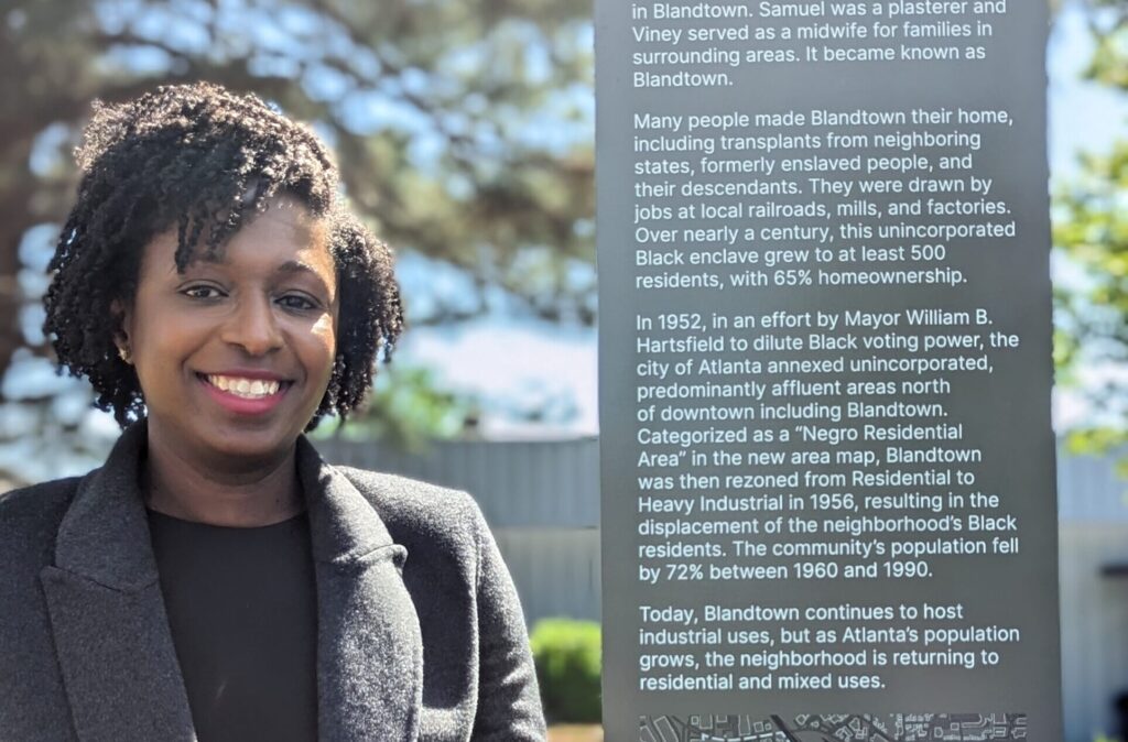 Dr. Rhana Gittens Wheeler with one of the signs she authored at Blandtown in Atlanta