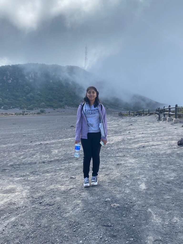 Arleni Huerta standing in front of active volcano Irazu Volcano in Costa Rica.