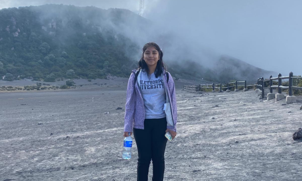 Arleni Huerta standing in front of active volcano Irazu Volcano in Costa Rica.