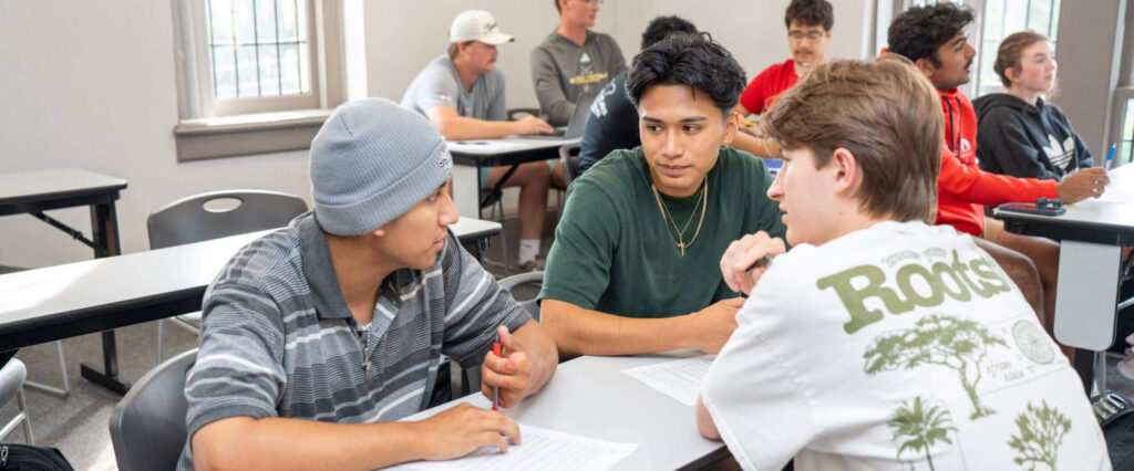 Three students discuss around a table