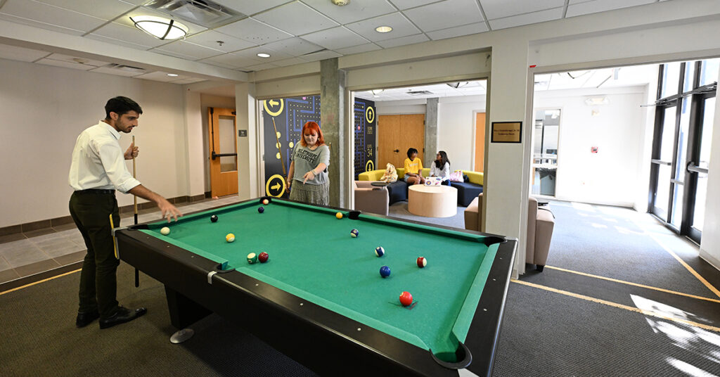 Students shoot pool in residence hall common room