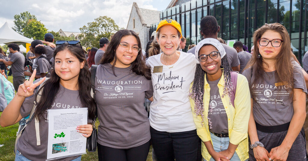 four students with the president on the quad