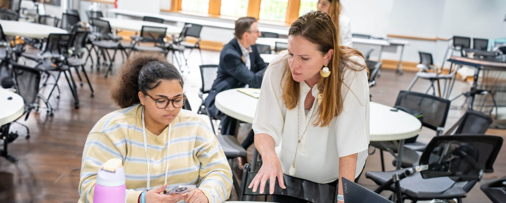 Dr. Keib works with a student at a table.