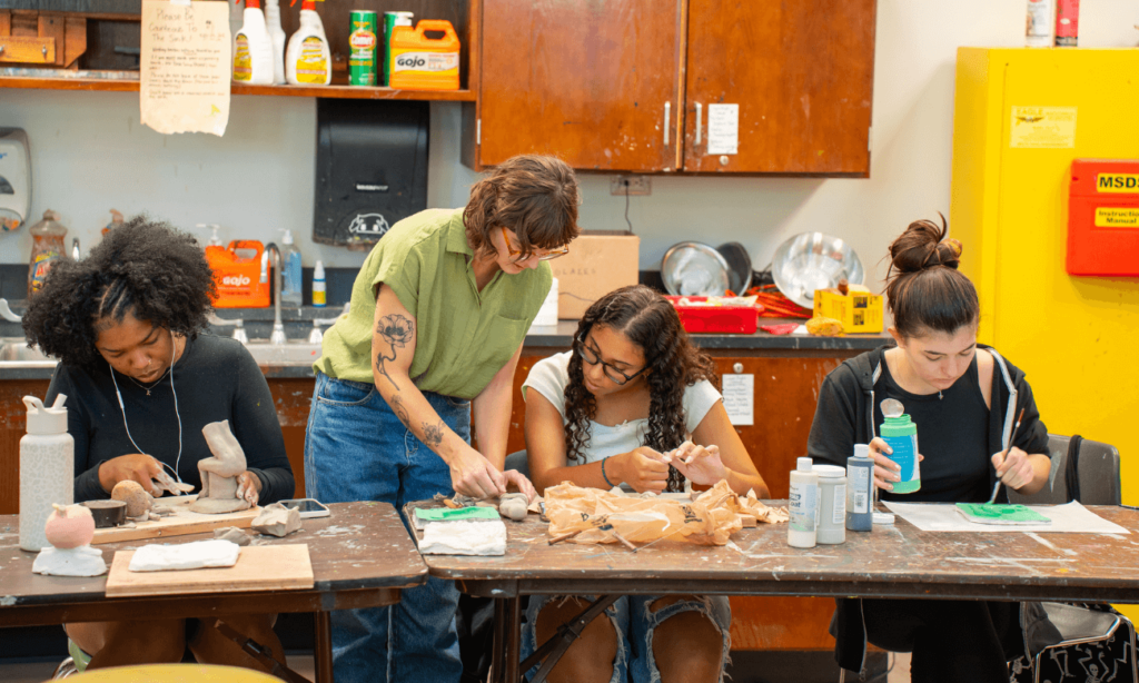 Studio art professor Abigail Gregg assists a student with their figure sculpting project.