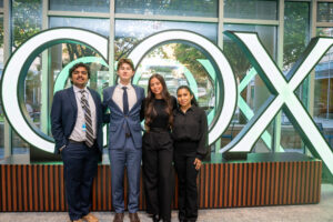 The student winners of the Cox case study competition in front of a "Cox" sign