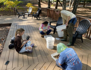 Professor and students conduct research on water samples from creek with a student filming them