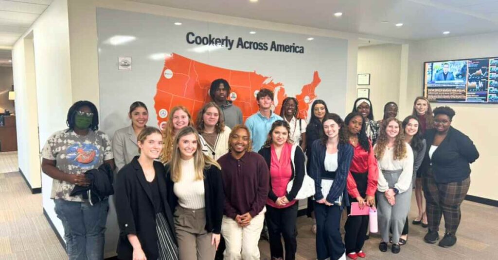 Students and Cookerly staff stand in front of a wall that says "Cookerly Across America"