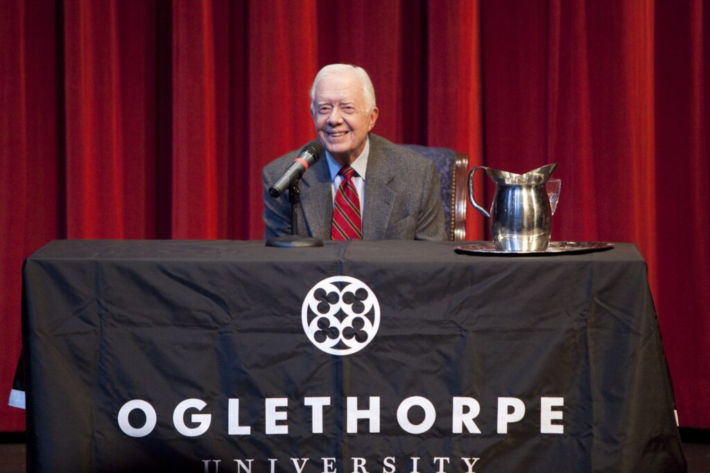President Jimmy Carter seated on a platform behind a table