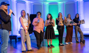 Penelope Bertrand with other students holding random objects like a stuffed snake animal and a jar of peanut butter to reflect their impromptu exhibition "COVID-19 lockdown at grandma's house."