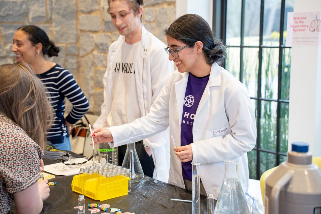 A student hands a test tube to a participant at the Atlanta Science Festival event in the Cousins Center for Science and Innovation