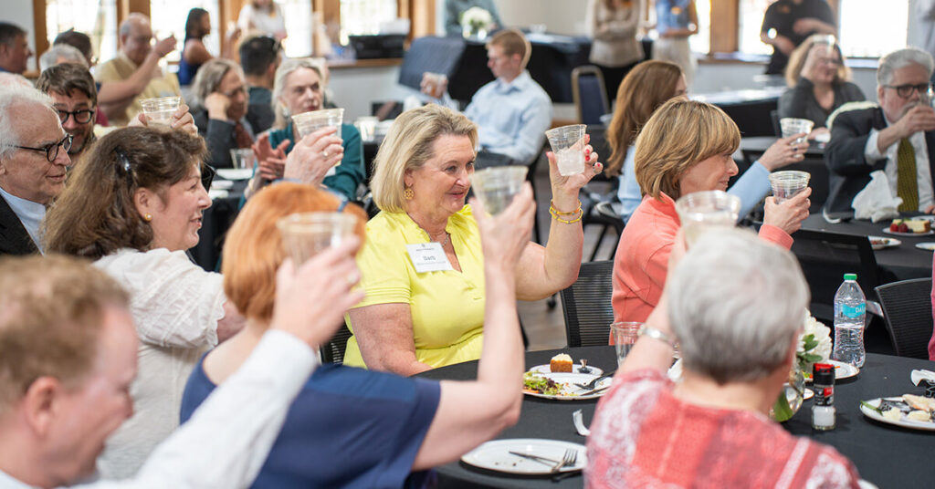 Faculty, staff, and guests raise a glass to toast retiring faculty members Lee Knippenberg and Dr. Brent Runnels.