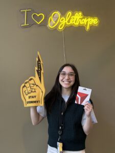 Mekela Iorio holding a yellow foam finger and a Delta gift card.