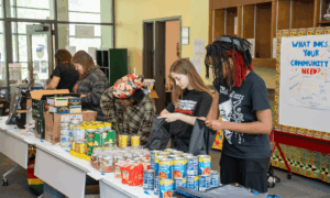 Students working in an assembly line to pack drawstring bags with canned goods for APS students.