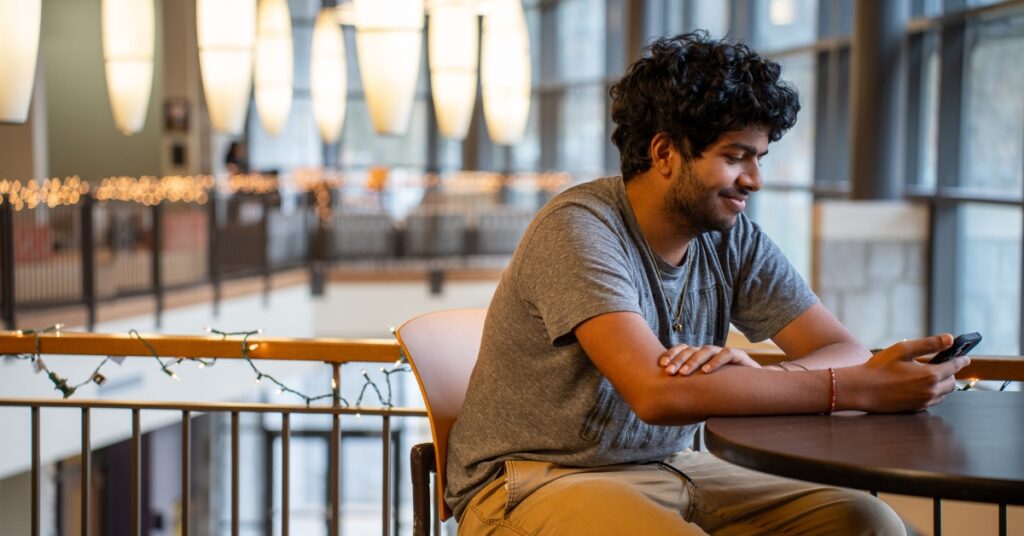 A smiling students looks at their phone.
