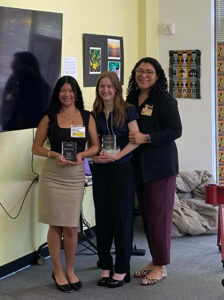 Yuliana Aceves and Emily Raider receive an award from Intercutural Center Director Marisol Zacarias.