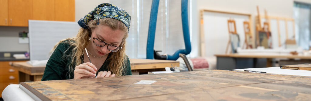 A student works to repair an ancient Japanese screen.
