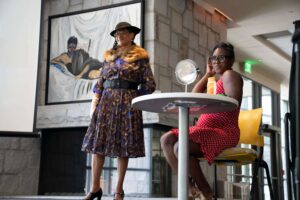 Dr. Michelle Lyn and Maya Wells in costumes performing a skit about Madame Cj Walker.