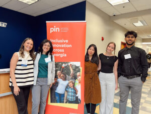 Group of student interns stand in front of a sign that reads "Inclusive innovation across Georgia."