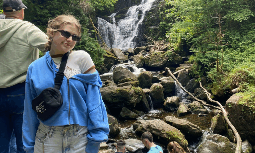 Tatum McBride, Theatre major stands in front of a waterfall on Study Abroad in Ireland.