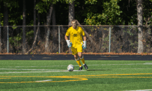 Jack Lowrie wearing Oglethorpe mens soccer jersey and goalie gloves on a soccer field.