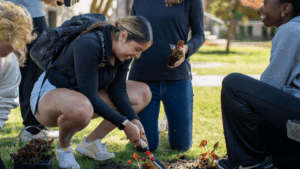 Karina Lopez smiling while digging a hold to plant a flower at an Earth Day service project.