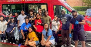 A group of student volunteers posing by a van