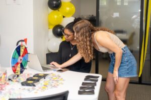Writing tutor helps student on her computer at the grand opening of their new space. 