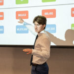 Man pointing at a projected presentation while presenting.