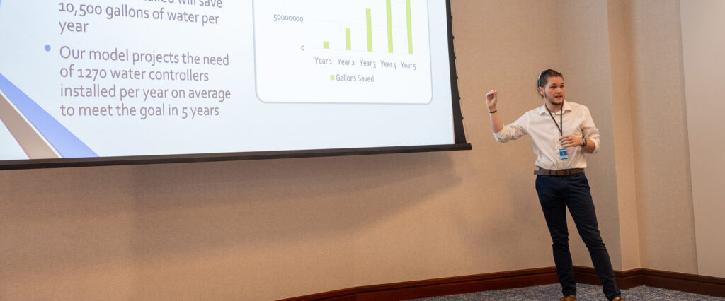 Man in a suit presents a projected slide.