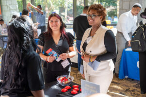 Two students in professional attire attending the career fair speak to an employer.