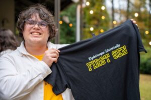 A student holds up a t-shirt that reads "Oglethorpe University First Gen"