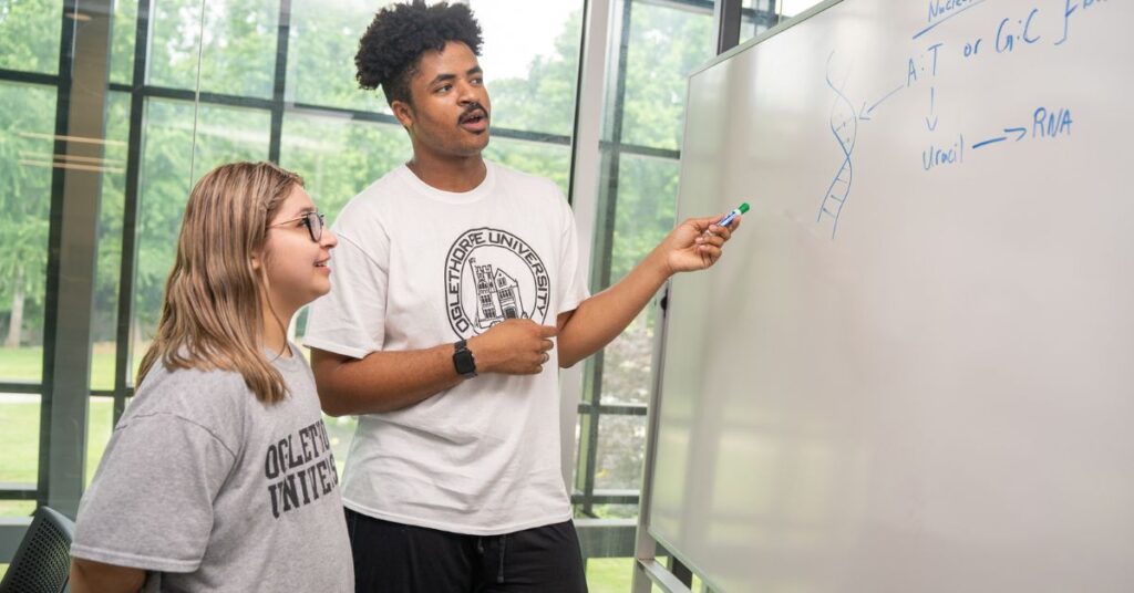 Two students examine a whiteboard with notes on it