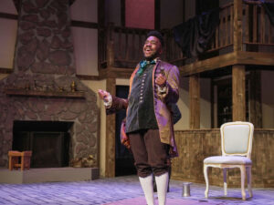 Student in theatre costume on a decorated stage set.
