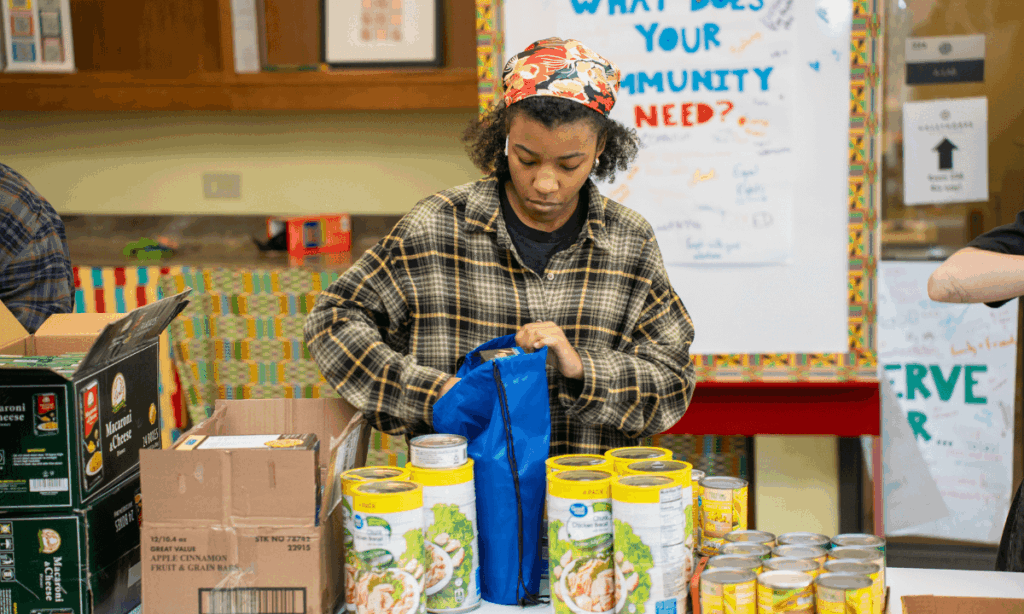 Student volunteer packing canned foods in backpack.