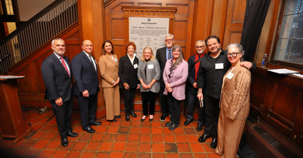 Group of individuals stand in front of Gray Stone wall.