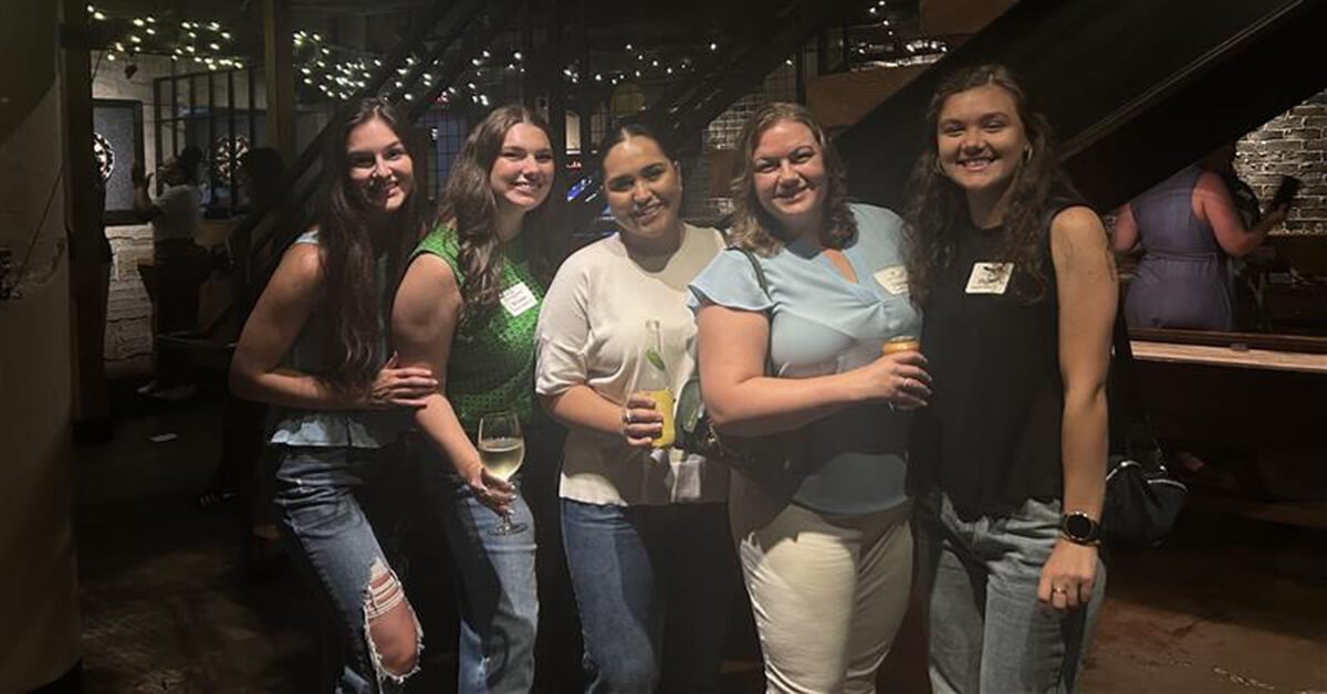 Alumni pose in a local restaurant for a photo during an alumni event.