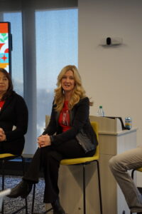 Debbie Bachmann wears a red Coca-Cola shirt and sits on an Oglethorpe alumni panel. 