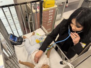 Student using a stethoscope on a medical manikin baby. 