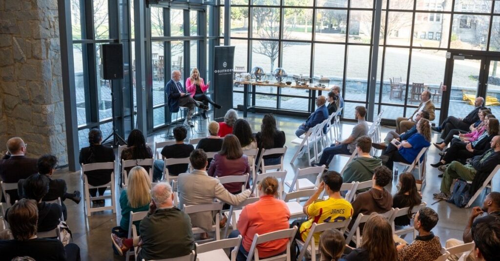 An audience listens to two speakers