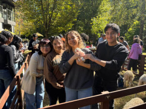 Students pose for a photo holding an animal at a petting zoo.