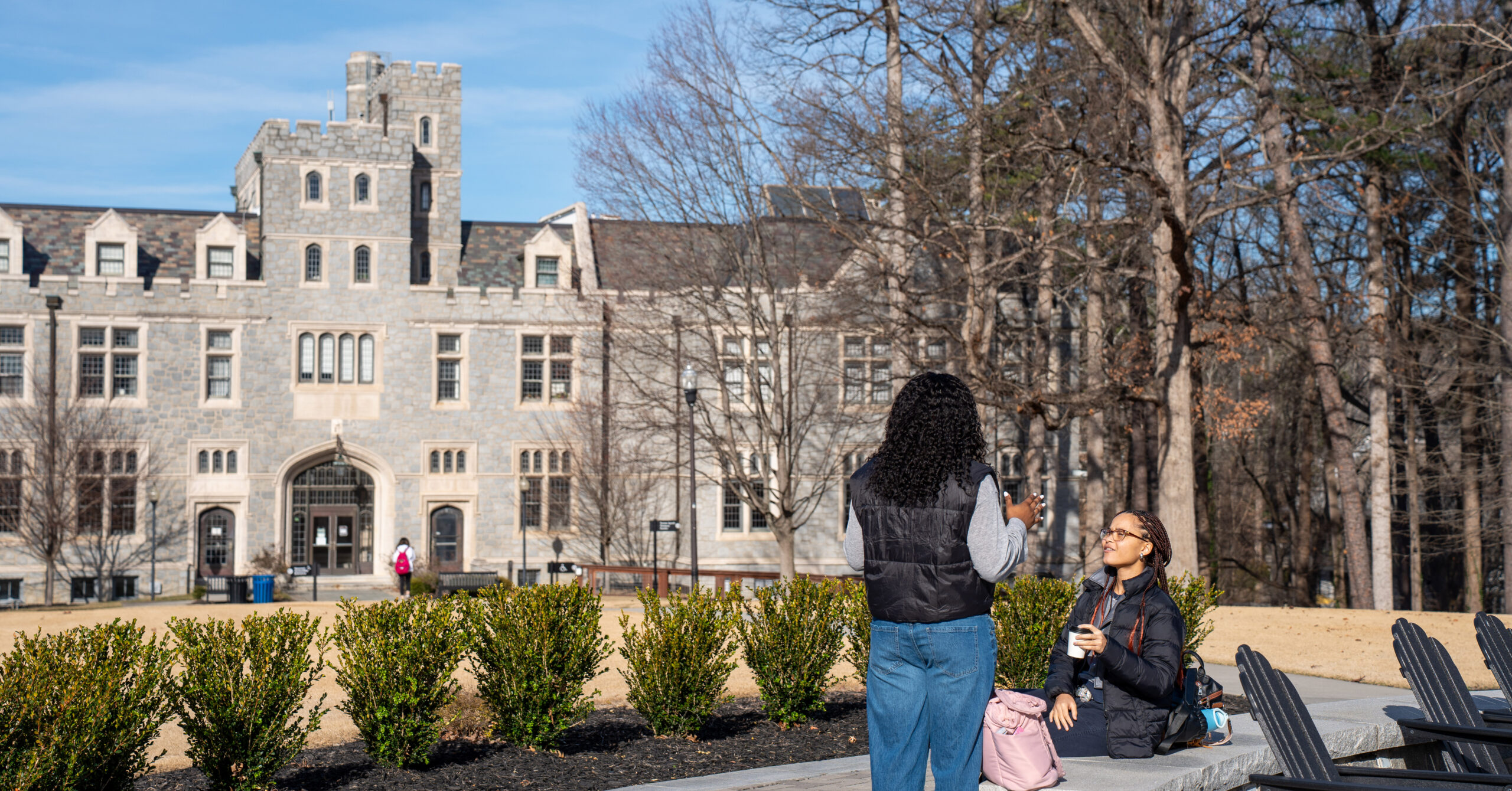 Two students sit in Dubose circle in front of Lowry Hall